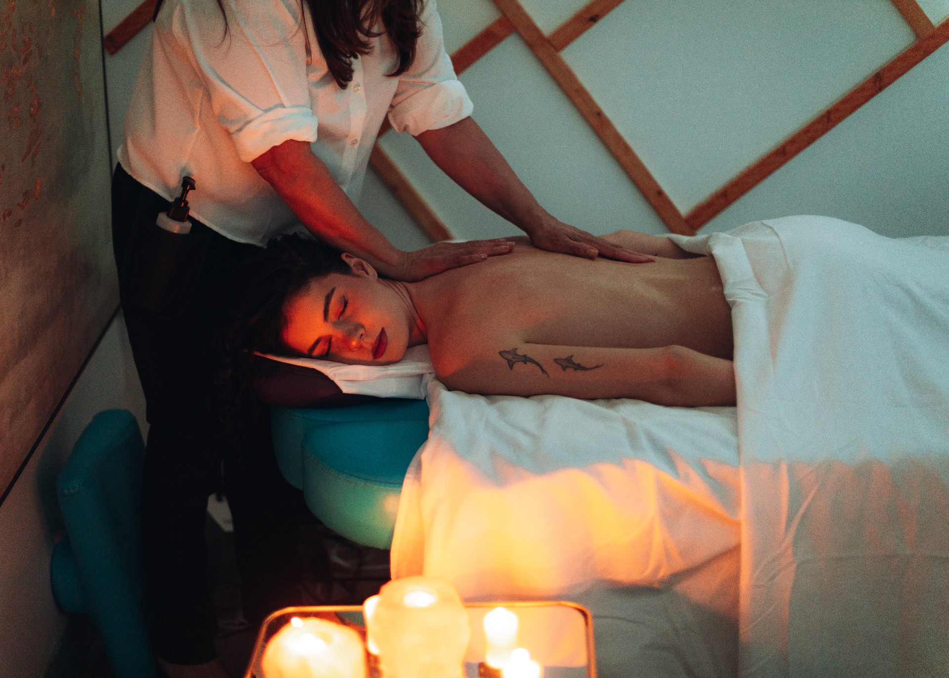 Therapist performing a relaxing massage on a guest in a warmly lit, candlelit room at HBL Spa in Alexandria, VA