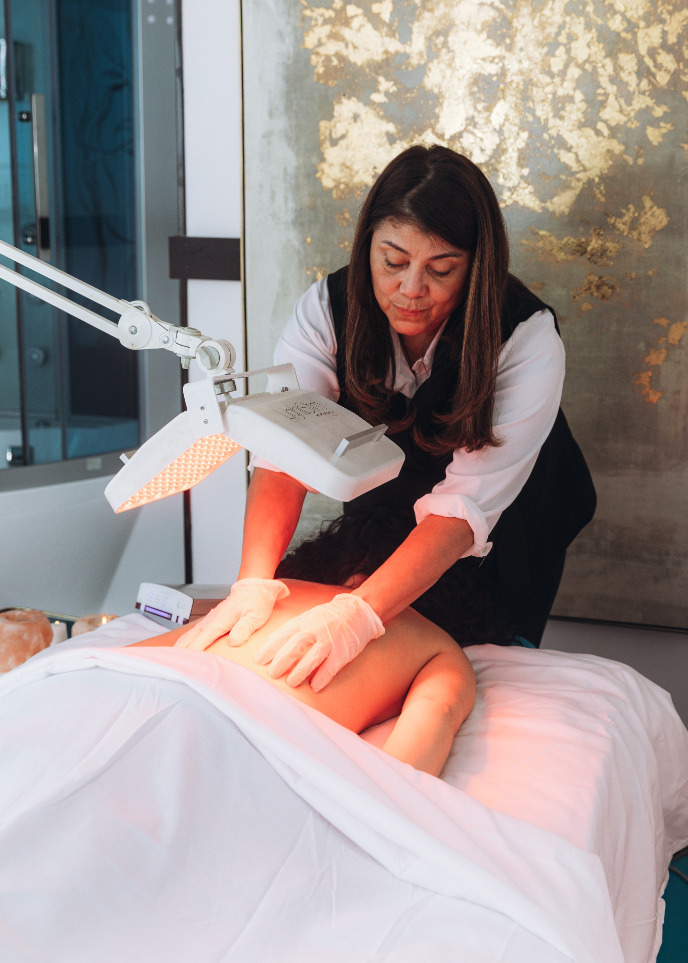 Licensed massage therapist working with red-light therapy at HBL Spa